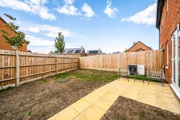 Rear garden with paved patio, airsource heat pump, lawn and fenced boundaries.