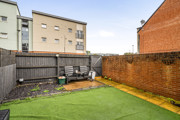 Enclosed rear garden with lawn, paved area and surrounding walls.