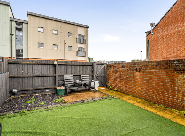 Enclosed rear garden with lawn, paved area and surrounding walls.