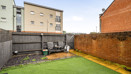 Enclosed rear garden with lawn, paved area and surrounding walls.