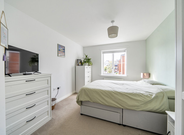 Bedroom with double bed, chest of drawers, television and window.