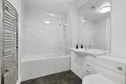 Bathroom with bathtub, shower screen, sink, toilet, and white tiled walls.