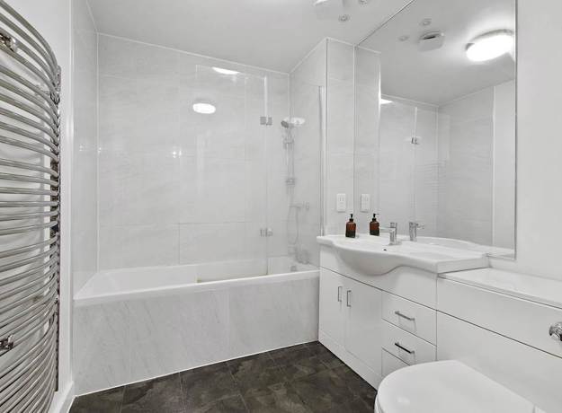 Bathroom with bathtub, shower screen, sink, toilet, and white tiled walls.