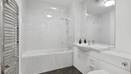 Bathroom with bathtub, shower screen, sink, toilet, and white tiled walls.