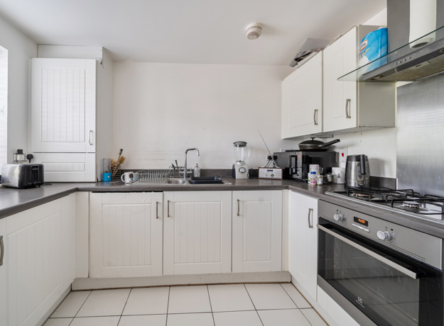 Modern white kitchen with cabinets, gas hob, and black countertops.