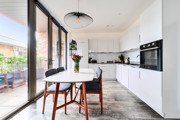 Dining area with table and chairs next to balcony doors and kitchen.