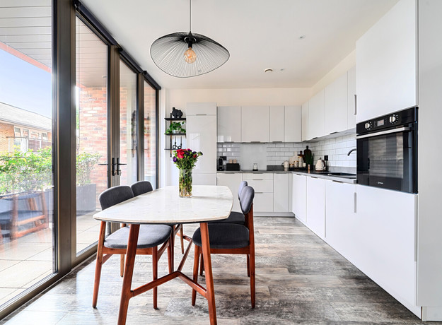 Dining area with table and chairs next to balcony doors and kitchen.