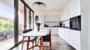 Dining area with table and chairs next to balcony doors and kitchen.