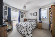 Bedroom with patterned bedding, shelving units and a window with curtains.