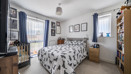 Bedroom with patterned bedding, shelving units and a window with curtains.