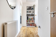 Hallway with wood-effect floor, radiator, and shelving unit.