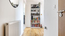 Hallway with wood-effect floor, radiator, and shelving unit.
