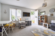 Living room with sofa, TV unit, dining table and doors opening to the garden.