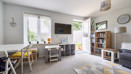Living room with sofa, TV unit, dining table and doors opening to the garden.