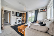 Living room with a sofa, coffee table, wall-mounted TV and balcony doors.