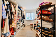 Walk-in wardrobe with shelving, hanging rails, storage and window.