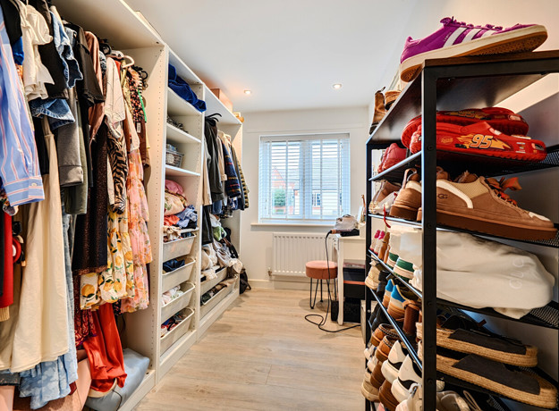 Walk-in wardrobe with shelving, hanging rails, storage and window.