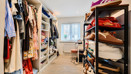 Walk-in wardrobe with shelving, hanging rails, storage and window.