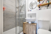 Ensuite with shower enclosure, sink, toilet, and wall shelf.