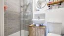 Ensuite with shower enclosure, sink, toilet, and wall shelf.