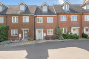 Row of red brick terraced houses with parking spaces at the front.
