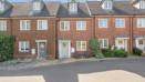 Row of red brick terraced houses with parking spaces at the front.