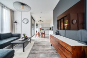 Open-plan living area with sofa and media unit, leading into kitchen.
