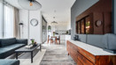 Open-plan living area with sofa and media unit, leading into kitchen.