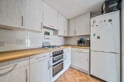 Bright fitted kitchen with light wood cabinets, wood-effect worktops, integrated oven, and freestanding fridge freezer.
