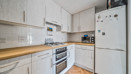 Bright fitted kitchen with light wood cabinets, wood-effect worktops, integrated oven, and freestanding fridge freezer.