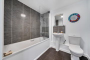 Bathroom with bathtub, wall tiles, sink and toilet.