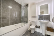 Bathroom with bathtub, toilet, sink, and tiled walls.