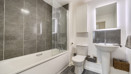Bathroom with bathtub, toilet, sink, and tiled walls.