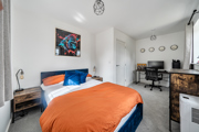 Bedroom with double bed, desk, chair and wall artwork.