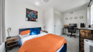 Bedroom with double bed, desk, chair and wall artwork.