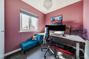 Home office with desk, computer setup, chair and window.