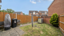 Garden with paving slabs, lawn, wooden fence, and bins near the patio.