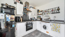 Kitchen with fitted units, oven, washing machine, fridge-freezer and wall shelving.