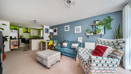 Open-plan living area with armchairs, sofa and breakfast bar leading into kitchen.