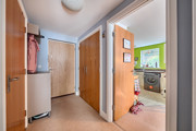 Hallway with doors and view into the kitchen.