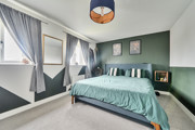 bedroom with double bed, bedside tables, green wall and window with curtains.