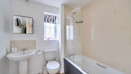 Bathroom with sink, toilet and bathtub with shower screen.