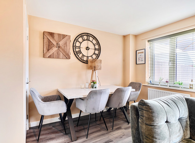Open-plan dining area with table, chairs and large window.