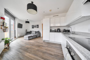 Open-plan living area with kitchen, sofa and large windows.