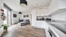 Open-plan living area with kitchen, sofa and large windows.