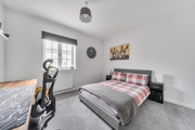 Bedroom with double bed, desk, and window with grey carpet.