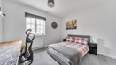 Bedroom with double bed, desk, and window with grey carpet.