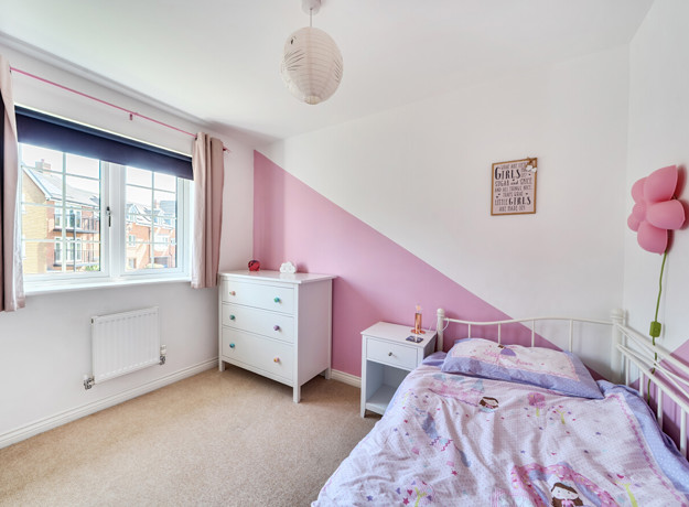 Child’s bedroom with pink accents, bed, and window.