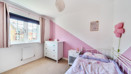Child’s bedroom with pink accents, bed, and window.