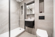 Bathroom with shower enclosure, vanity unit, mirror and wall-mounted cabinet.